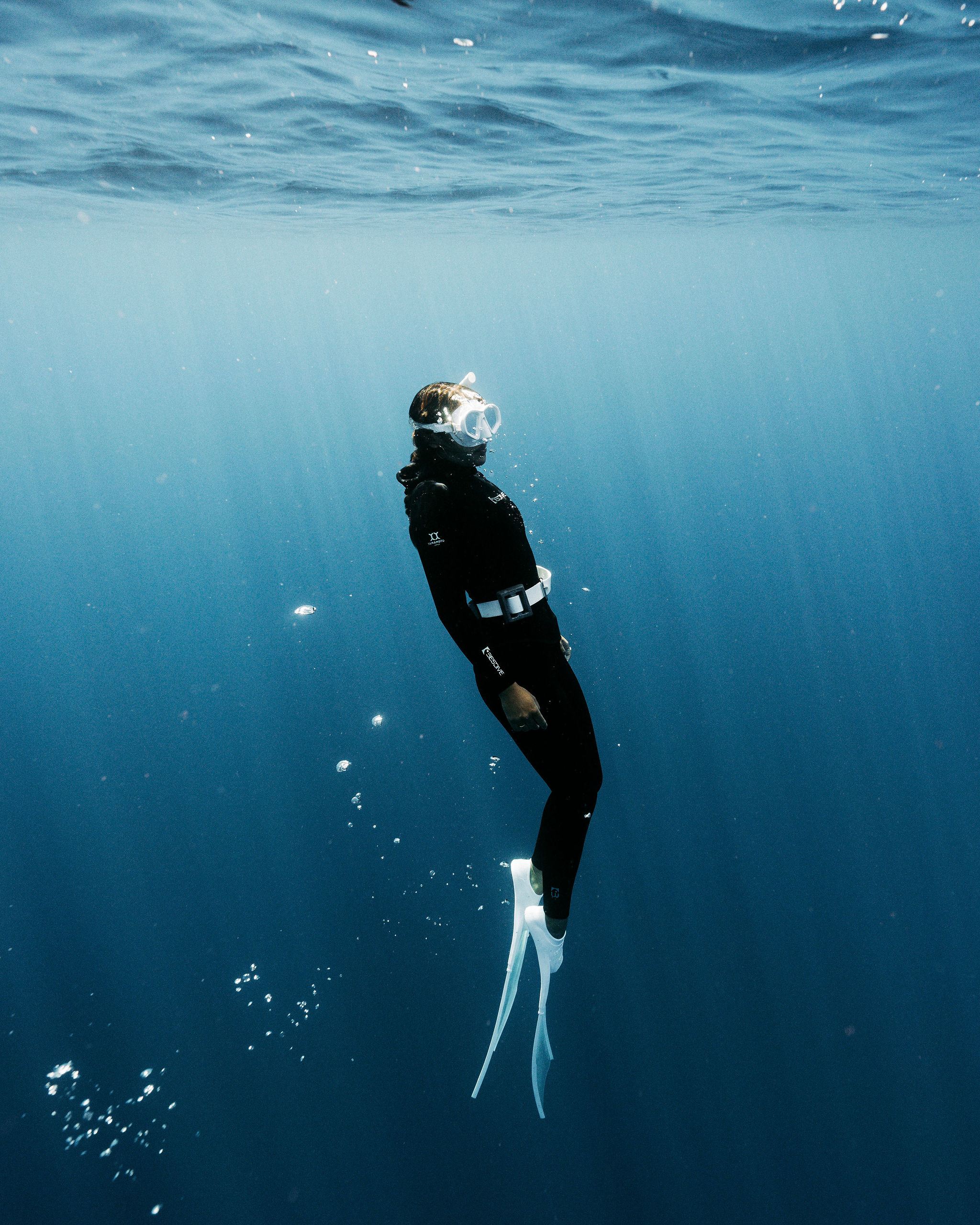 Freediver descending head-first into deep blue water