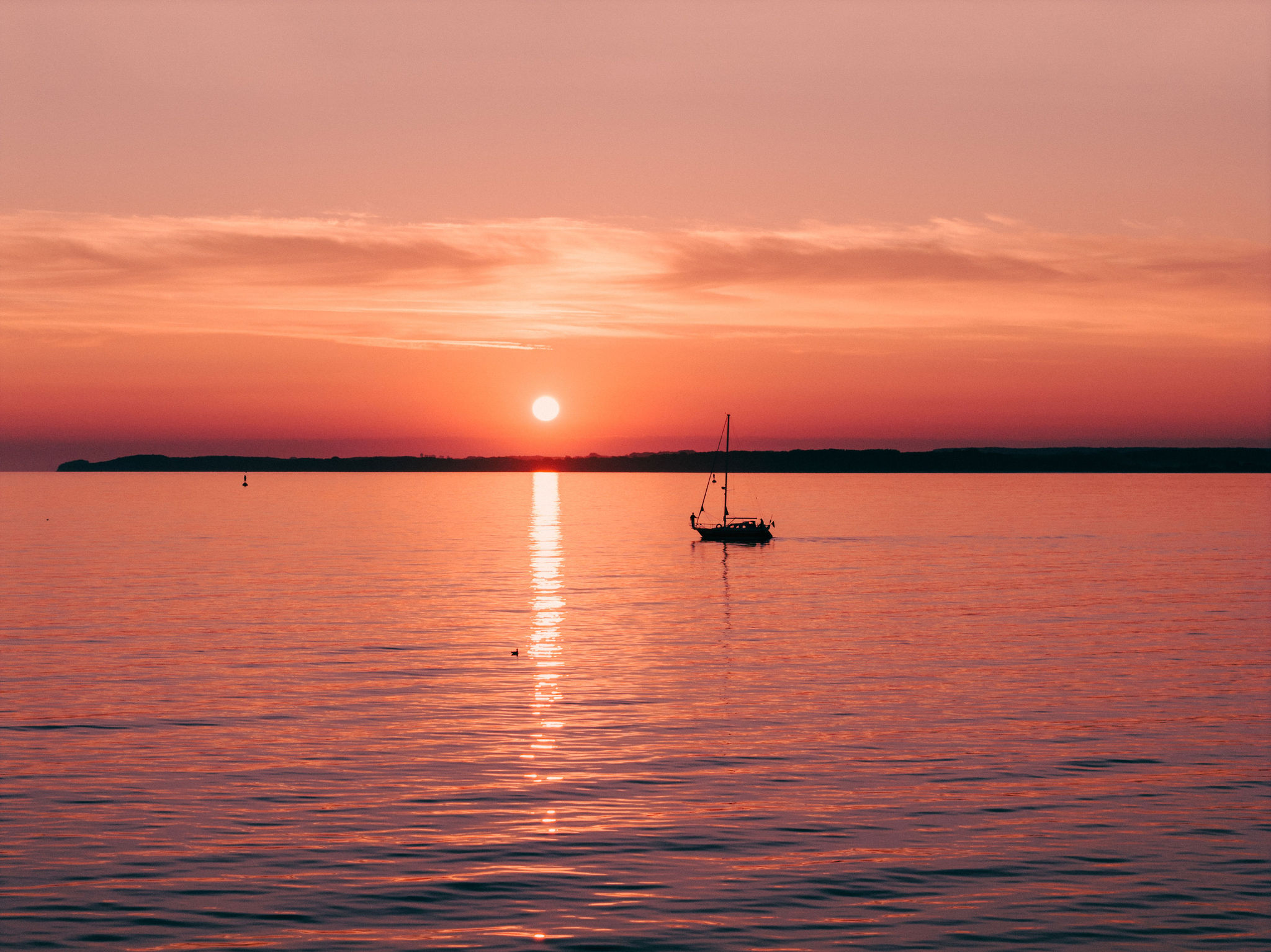 Sailboat anchored on the Baltic Sea under a red sunset