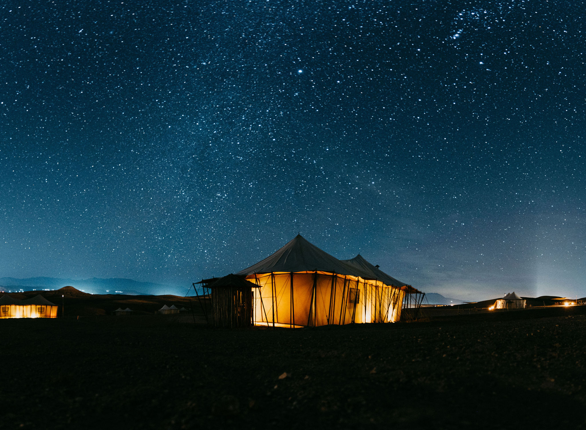 Desert camp lit up under a starry night sky