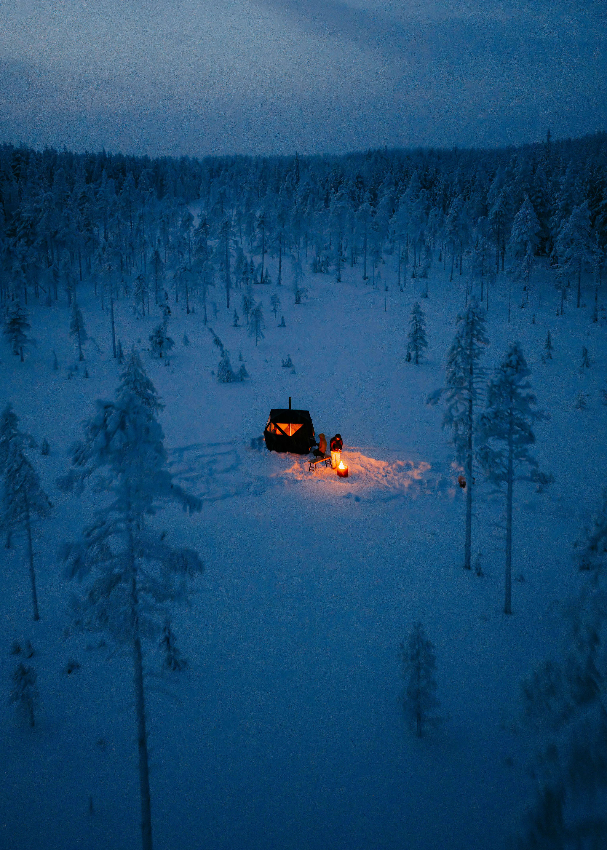 Wilderness sauna tent glowing at dusk in the Lapland snow